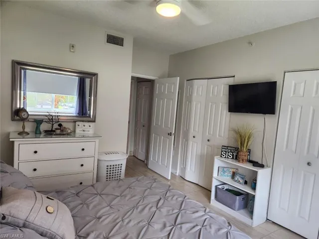 Bedroom with multiple closets, a textured ceiling, a ceiling fan, and light wood-style flooring