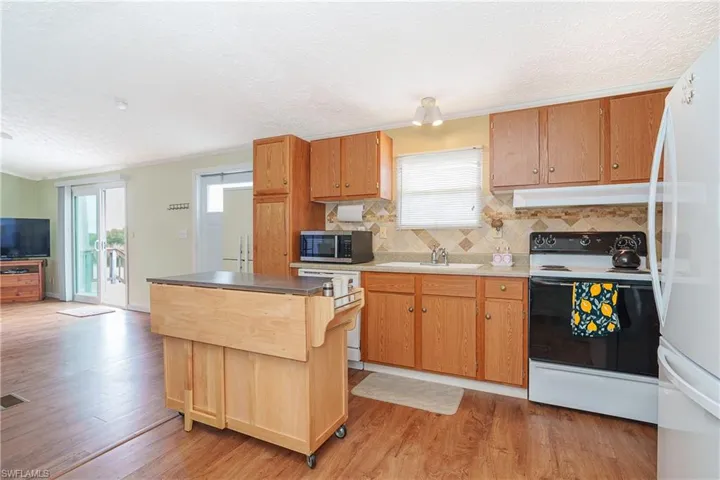 Kitchen with white appliances, ornamental molding, light wood-style floors, light countertops, and wood finish cabinets