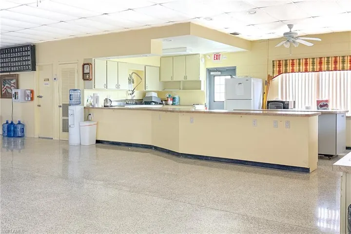 Kitchen featuring a paneled ceiling, a peninsula, freestanding refrigerator, light countertops, and ceiling fan
