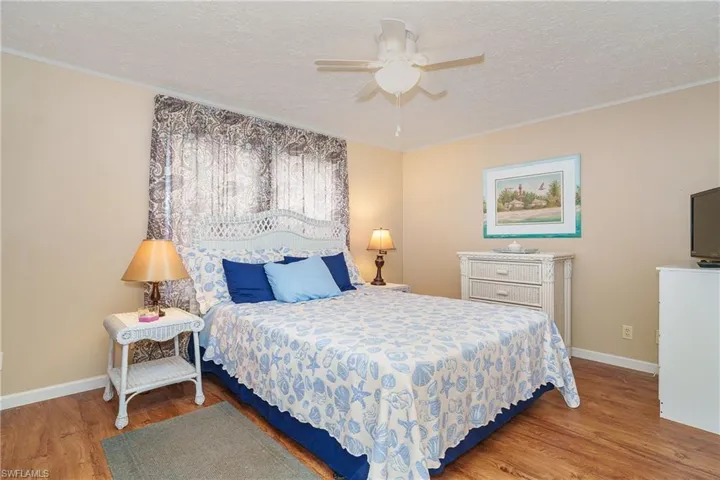 Bedroom with a textured ceiling, light wood-style floors, and a ceiling fan