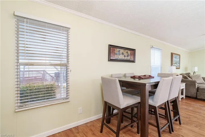 Dining area featuring ornamental molding, light wood finished floors, and a textured ceiling