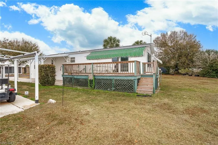 Back of property with a lawn and a wooden deck