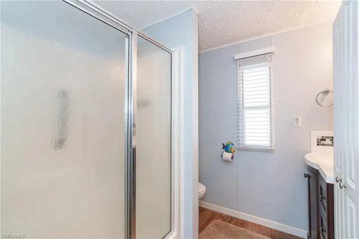 Full bathroom featuring vanity, a shower stall, a textured ceiling, and dark wood-style flooring