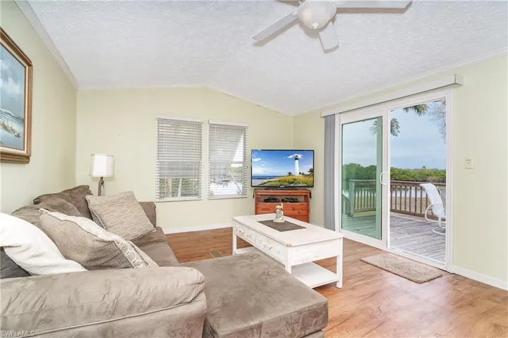 Living area with ceiling fan, wood finished floors, and crown molding