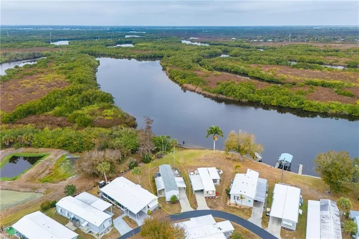 Aerial perspective of suburban area featuring a nearby body of water and a forest