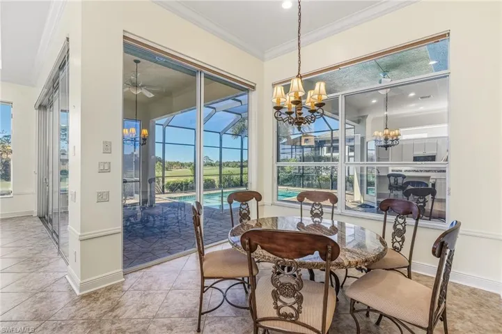 Dining area featuring ornamental molding, a sunroom, a chandelier, light tile patterned flooring, and plenty of natural light