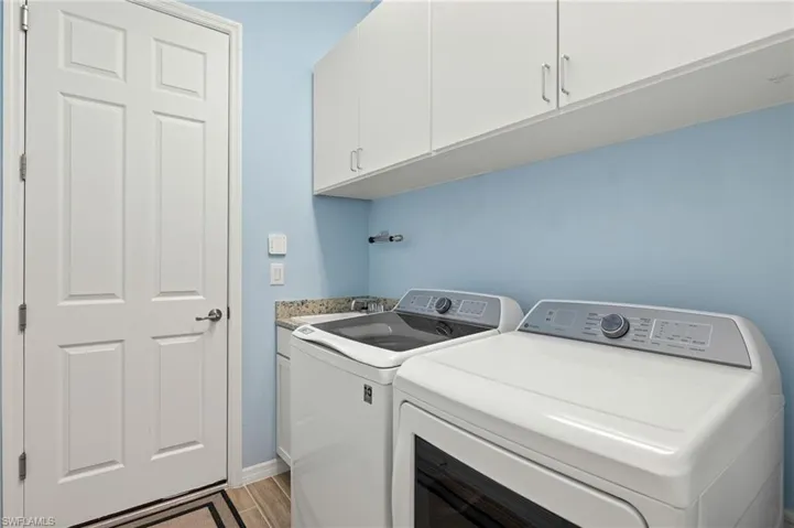 Laundry area with cabinet space, independent washer and dryer, light wood finished floors, and a sink
