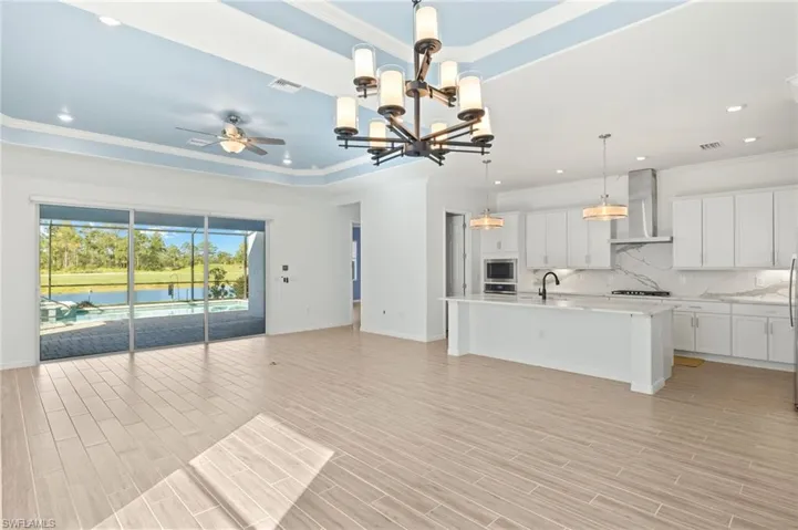 Unfurnished living room featuring ornamental molding, a ceiling fan, recessed lighting, light wood-style flooring, and a chandelier