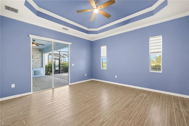 Unfurnished room featuring a raised ceiling, a ceiling fan, wood finished floors, and ornamental molding
