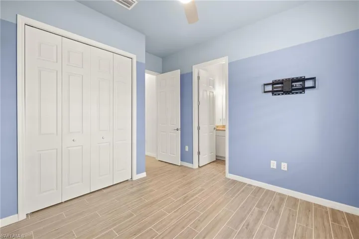 Unfurnished bedroom with a closet, light wood-type flooring, connected bathroom, and a ceiling fan