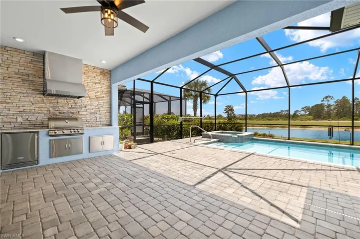 View of swimming pool featuring a grill, a patio area, a lanai, and exterior kitchen