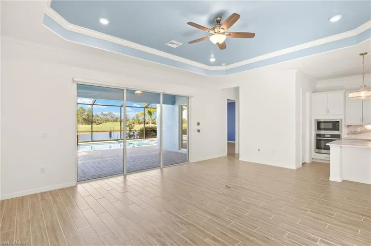 Unfurnished living room with a raised ceiling, a ceiling fan, ornamental molding, light wood-style floors, and recessed lighting