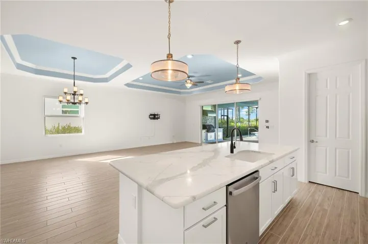 Kitchen featuring dishwasher, a ceiling fan, open floor plan, light wood-style flooring, and white cabinets