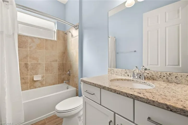 Full bathroom with vanity, shower / tub combo with curtain, and wood finished floors