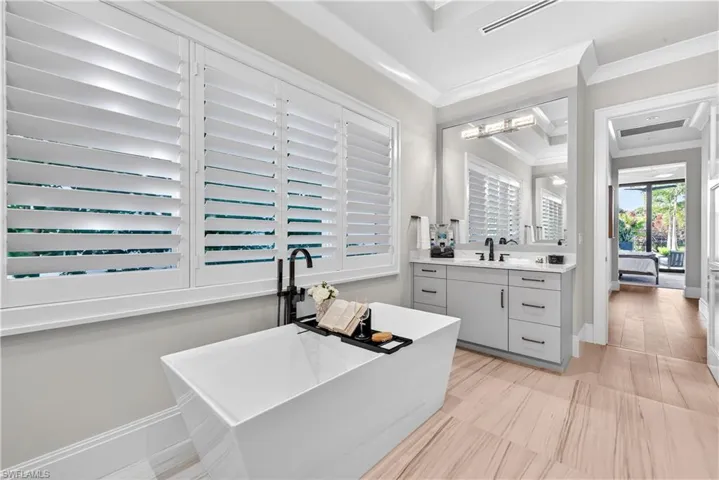 Bathroom featuring vanity, a soaking tub, and crown molding