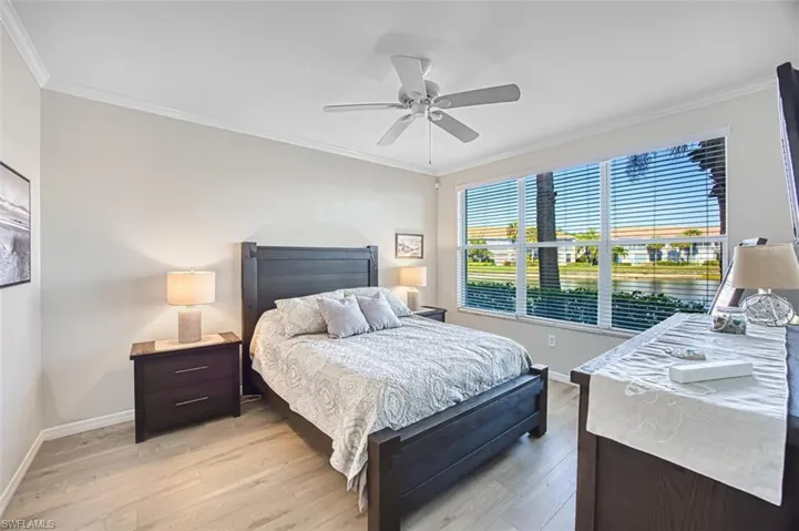 Bedroom with ornamental molding, light wood finished floors, and a ceiling fan