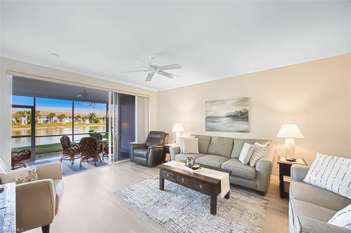 Living area with a water view, wood finished floors, and ornamental molding