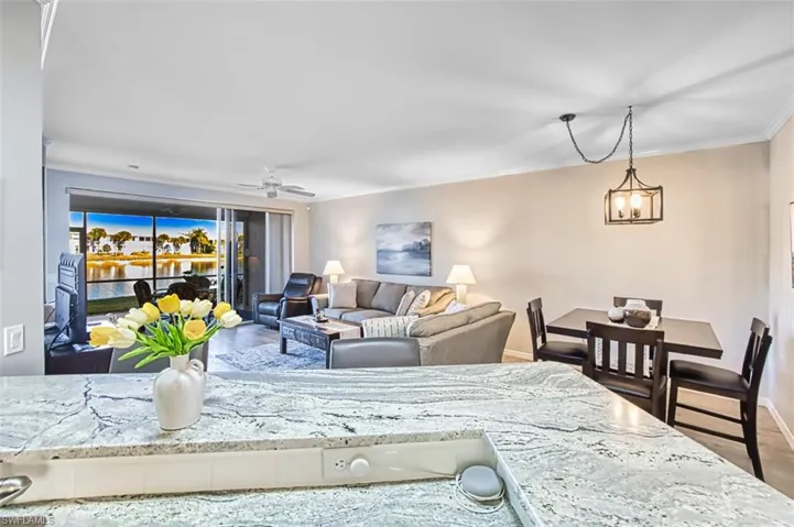 Living area featuring wood finished floors, a ceiling fan, and crown molding