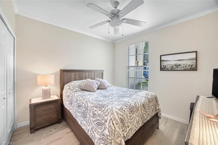 Bedroom featuring a closet, ornamental molding, light wood finished floors, and a ceiling fan