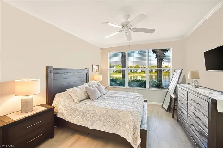 Bedroom featuring light wood-type flooring, crown molding, and ceiling fan