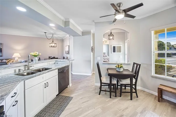 Kitchen featuring white cabinets, light stone counters, open floor plan, stainless steel dishwasher, and light wood-style flooring