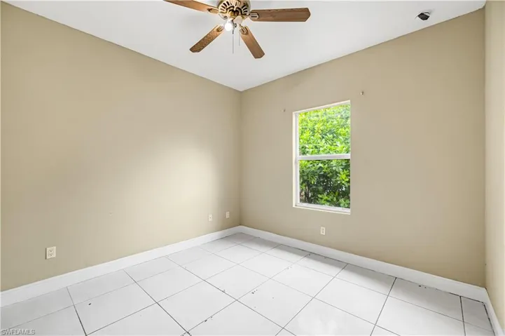 Empty room featuring light tile patterned flooring and a ceiling fan