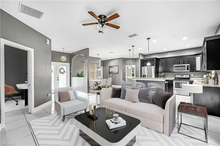 Living room featuring light tile patterned floors, a ceiling fan, an office area, and recessed lighting - This photo is virtually staged