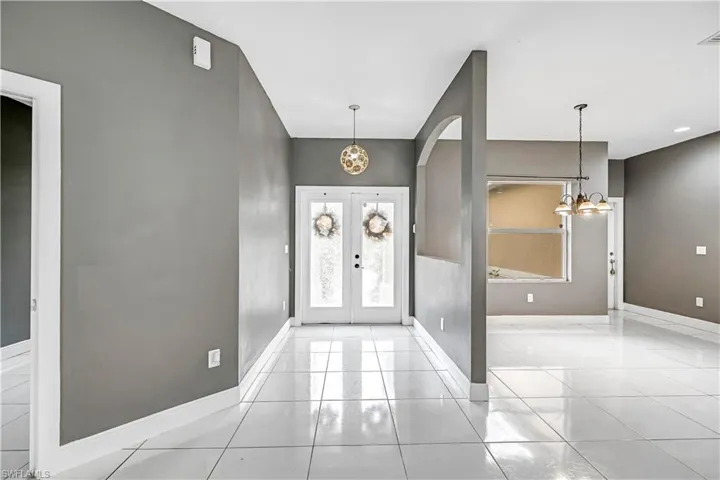 Foyer entrance featuring a chandelier, light tile patterned floors, french doors, and arched walkways
