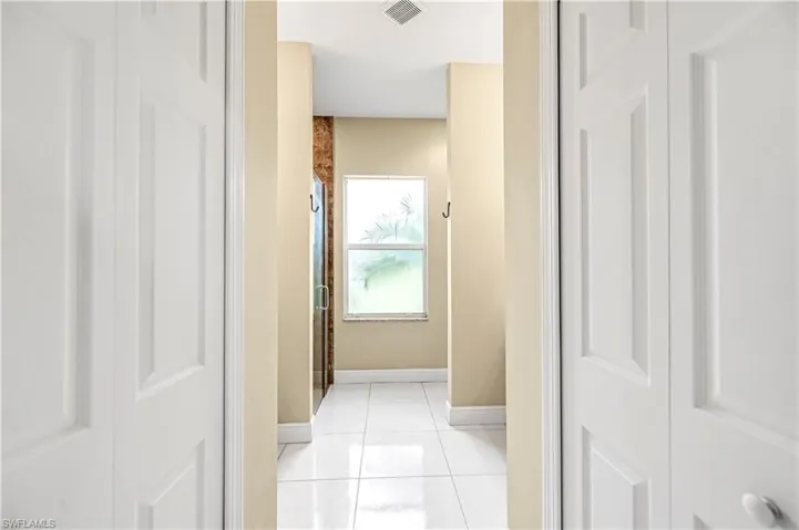 Corridor featuring light tile patterned flooring and baseboards