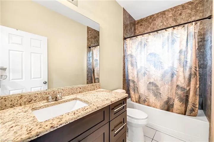 Bathroom with shower / tub combo with curtain, vanity, and light tile patterned floors