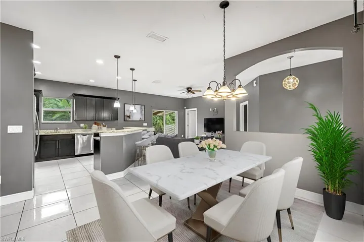 Dining area with ceiling fan, light tile patterned floors, recessed lighting, arched walkways, and a chandelier - This photo is virtually staged
