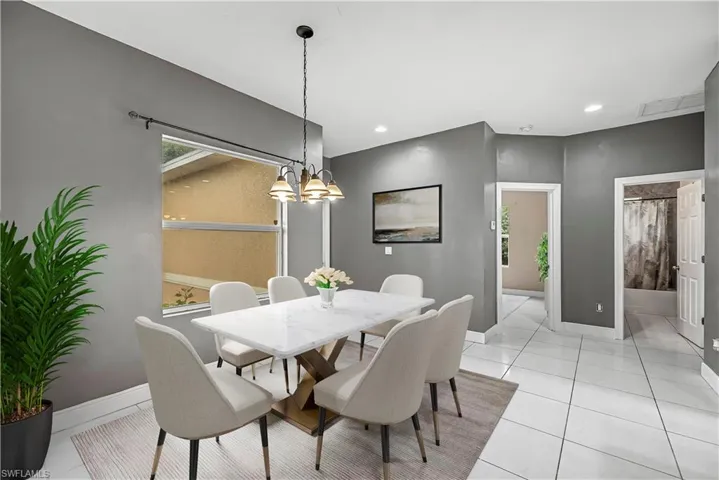 Dining area with light tile patterned floors, a chandelier, and recessed lighting - - This photo is virtually staged