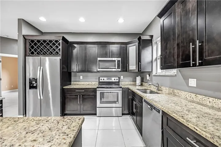 Kitchen featuring appliances with stainless steel finishes, light tile patterned flooring, light stone countertops, and recessed lighting
