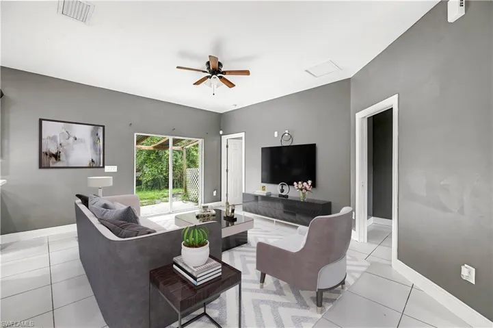 Living room featuring ceiling fan, light tile patterned flooring, and attic access