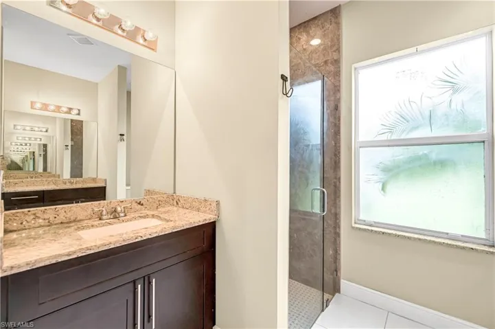 Full bathroom featuring a shower stall, light tile patterned floors, and vanity