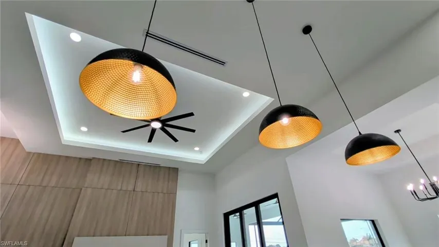 Tray ceiling featuring recessed LED lighting, geometric black-and-gold pendant fixtures, and an integrated ceiling fan
