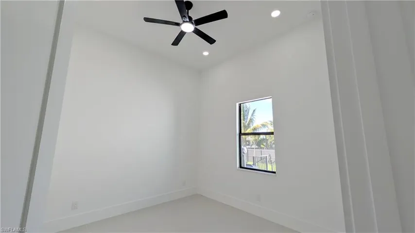 High-ceilinged room featuring recessed lighting, a matte black ceiling fan, and a single-pane window with dark trim