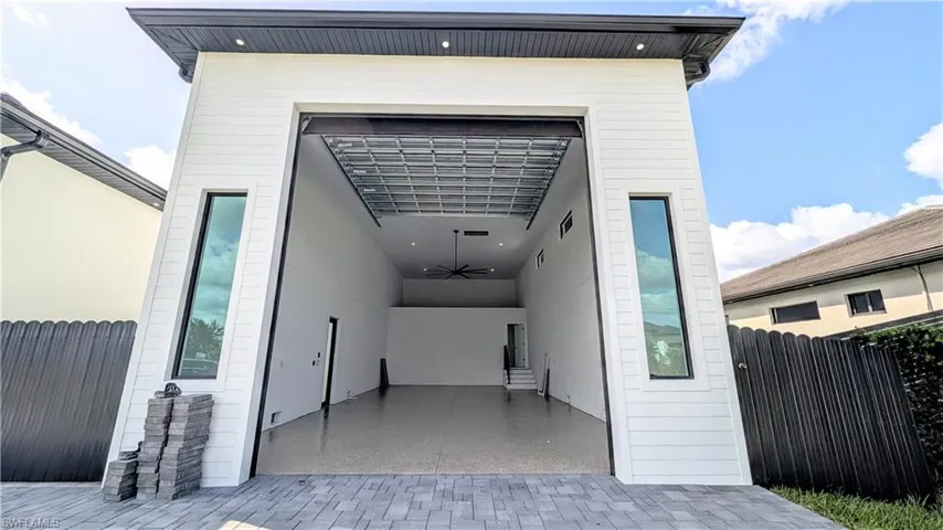 High-clearance structure featuring horizontal lap siding, a large overhead roll-up door, tall vertical windows, epoxy flooring, and recessed ceiling lighting