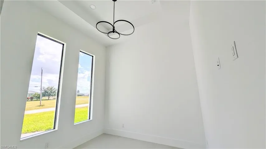 Tall ceilings with recessed lighting, dual floor-to-ceiling windows, and a modern circular chandelier