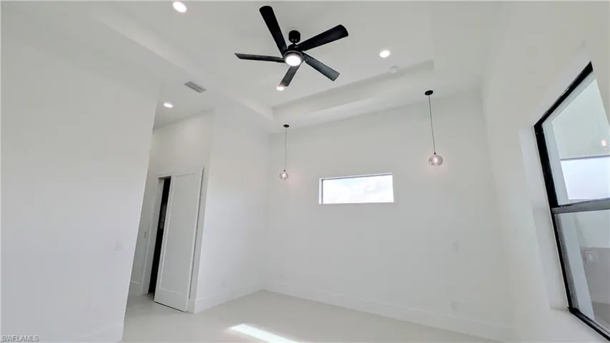 Tray ceiling featuring a matte black ceiling fan, recessed lighting, and dual pendant light fixtures with glass shades