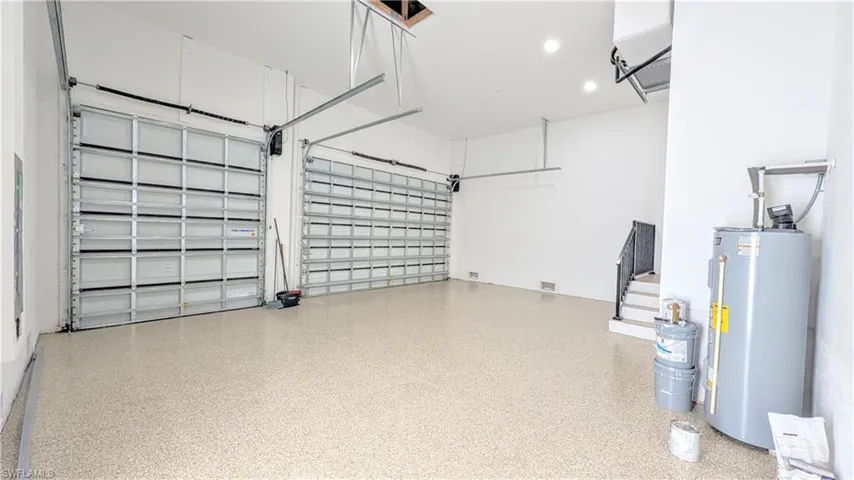 Three-car garage featuring epoxy flooring, recessed ceiling lighting, and two metal sectional garage doors