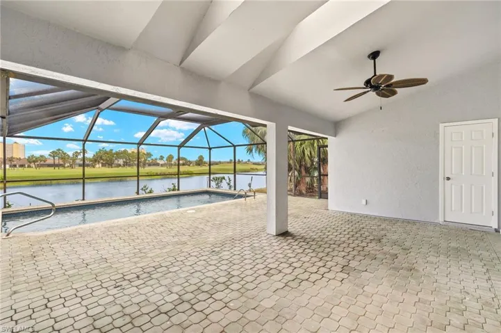 Swimming pool with a water view, a ceiling fan, a patio, and glass enclosure