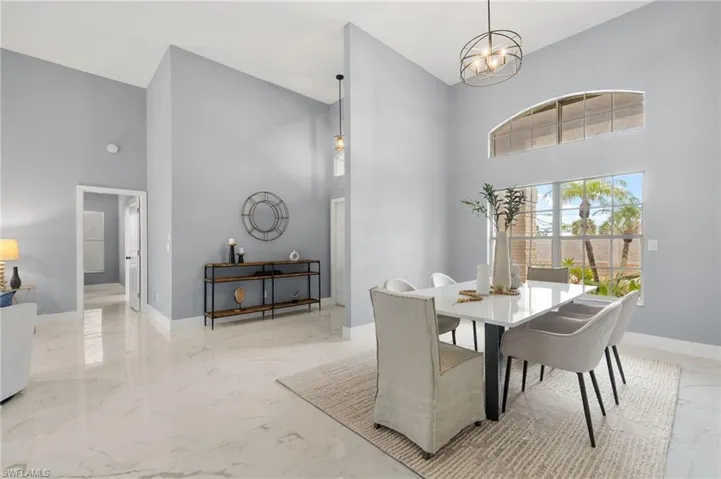 Dining room with a high ceiling, marble tiled floors, baseboards, and a chandelier