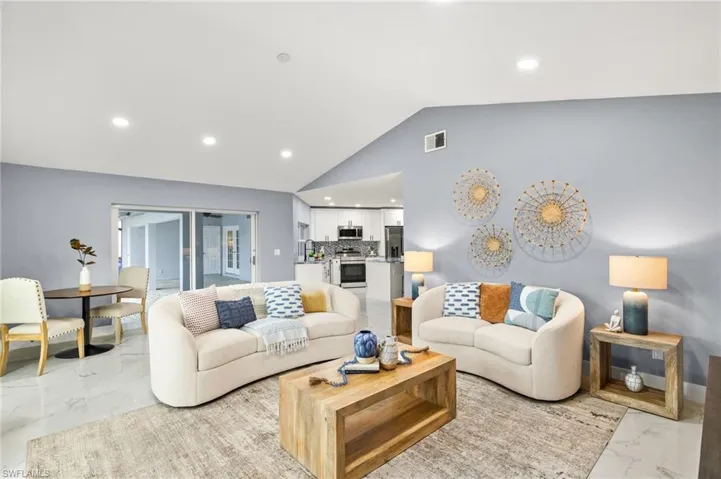 Living area with light marble finish floors, lofted ceiling, and recessed lighting