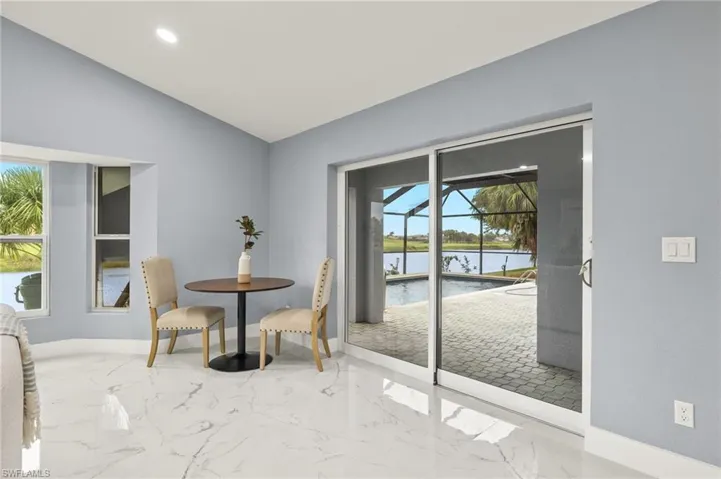 Dining area featuring a water view, baseboards, lofted ceiling, marble tiled floors, and recessed lighting