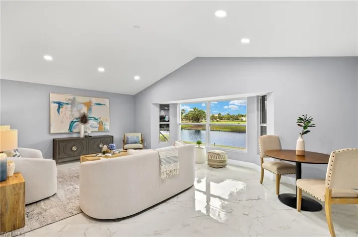 Living area with light marble finish flooring, recessed lighting, lofted ceiling, and a water view