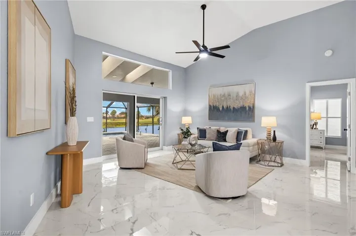 Living area featuring marble tiled flooring, baseboards, a water view, and high vaulted ceiling