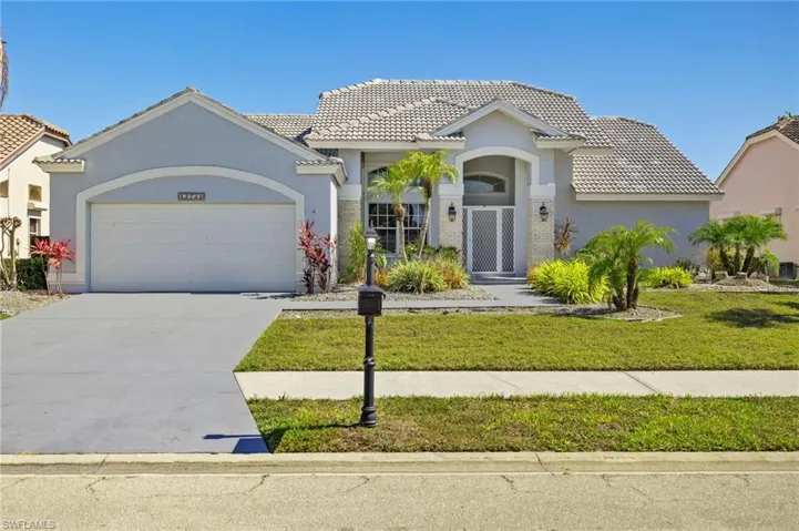 Mediterranean / spanish-style home with a tile roof, stucco siding, a garage, and driveway