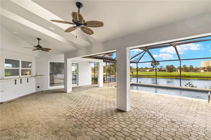 View of patio with a water view, a ceiling fan, an outdoor pool, and glass enclosure