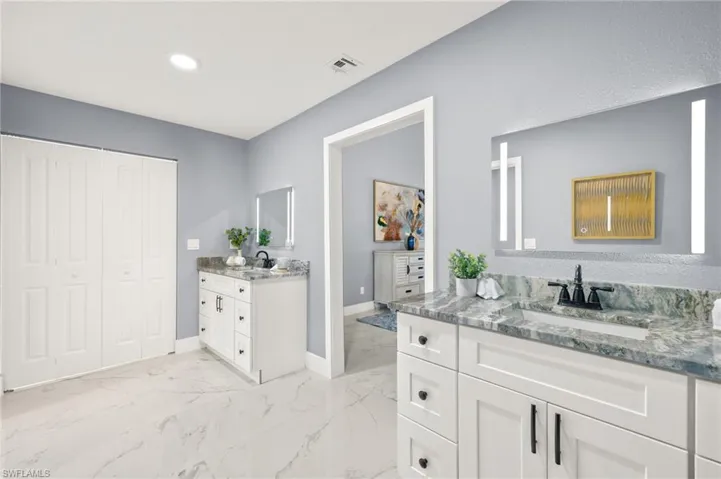 Bathroom with baseboards, marble finish floors, two vanities, and recessed lighting